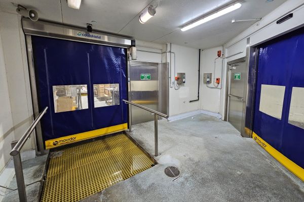 Two closed blue high speed doors inside a factory.