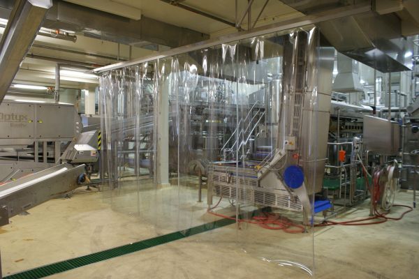 A clear plastic, PVC strip screen; industrial strip curtain used to protect factory equipment in commercial manufacturing facility